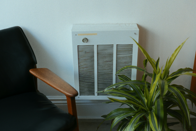 A happy person enjoying cool air from an air conditioner, symbolizing comfort and relief.